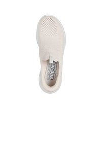 Zapato slip-on color crema de Skechers con parte superior de punto transpirable, superficie texturizada y suela de goma blanca. Cuenta con una lengüeta para facilitar su uso.