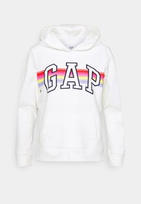 Felpa bianca con cappuccio e tasca frontale, con la scritta "GAP" in lettere in grassetto e un design a strisce multicolore sull'orlo del petto.