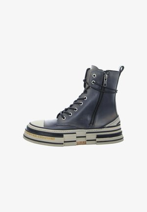 Chunky navy leather ankle boot with a high platform, rounded toe, lace-up front, and side zipper. Features black and beige striped sole.