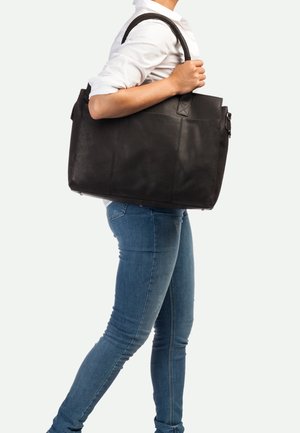 Borsa tote in pelle nera con doppi manici e design spazioso. Texture liscia con una leggera lucentezza, caratterizzata da cuciture visibili e una cerniera.