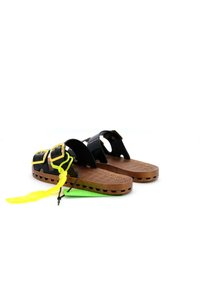 Zwarte sandalen met gele accenten, voorzien van een gestructureerde bruine zool, verstelbare banden en een uniek vetersysteem voor een veilige pasvorm.