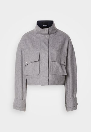 Grau verkürzte Jacke mit hohem Kragen, zwei vorderen Klappentaschen mit Druckknöpfen und langen Ärmeln mit Manschettendetails.