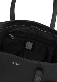 L'interno della borsa a tracolla in pelle nera presenta una tasca con zip, un logo discreto e una texture liscia con una fodera a motivo.