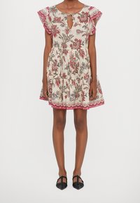 Robe à imprimé floral avec des manches courtes volantées, un décolleté en trou de serrure et une jupe à niveaux. Les couleurs incluent du crème, du rouge et du vert. Chaussures noires.