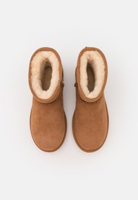 Stivali alla caviglia in suede marrone con fodera morbida color crema, design a punta rotonda e semplice cucitura lungo il bordo superiore.