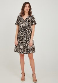 Svart och beige zebra mönster klänning med korta volangärmar, V-ringning och utsvängd kjol. Materialet verkar lätt och slätt.