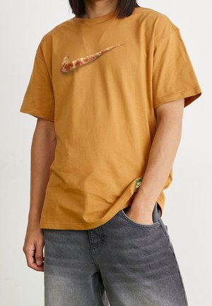 Kortærmet, sennepsgul bomulds T-shirt med et pizza-tema Nike swoosh logo. Casual pasform med en syet kant og sideetiket.