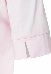 Light pink shirt sleeve featuring a split cuff design and subtle texture, made from lightweight fabric with neat stitching details.