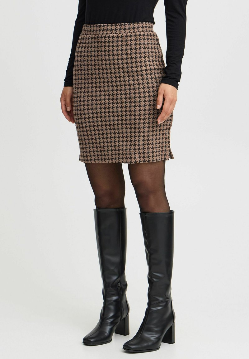 Rjava houndstooth svinčnik krilo s prilegajočim pasom in stranskimi razpoki, v kombinaciji z visokimi črnimi usnjenimi čevlji. Gladka tekstura in dolžina do kolen.
