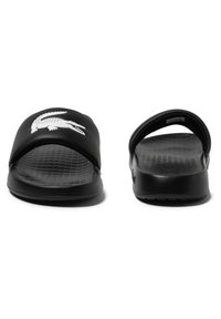 Black rubber slides with a textured sole and an open design. Features a white crocodile logo on the upper strap. Minimalistic shape.