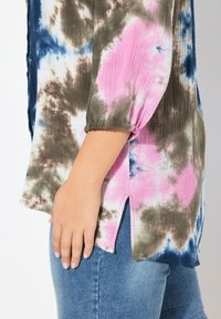 Camisa de teñido anudado multicolor con patrones en rosa, verde y azul; tela texturizada, mangas largas y cintas laterales para un detalle adicional.