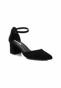 Zapato de tacón de ante negro con puntera afilada, correa en el tobillo y tacón cuadrado. Presenta una textura suave y un sutil logo en la plantilla.