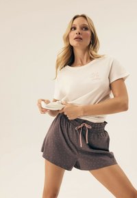 Light beige cotton t-shirt with "Can't wait for Sundays" print, paired with dark gray shorts featuring pink polka dots and adjustable drawstring.