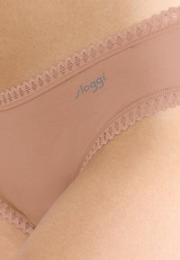 Lichtroze bikini ondergoed met een kanten rand bij de taille, zachte stof en een klein blauw logo aan de linkerkant.