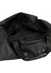 Grand sac de sport noir, fabriqué en tissu texturé, avec une ouverture zippée, des poignées robustes et un intérieur en tissu à motifs avec le logo "GUESS".