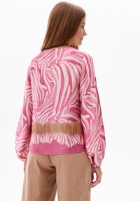 Roze zebraprint blouse met lange mouwen, met een vloeiende snit en elastische manchetten. Gladde, lichte stof met een verloopband aan de onderkant.