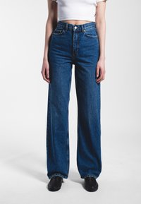 High-waisted blue denim jeans with a loose, wide-leg cut. Includes front pockets, belt loops, and a classic button closure.