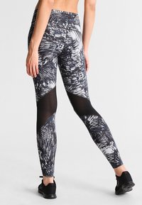 Legginsy w czarno-białe wzory z wysokim stanem, kontrastowymi panelami z siateczki i dopasowanym krojem. Odpowiednie do odzieży sportowej.