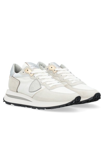 Baskets de sport blanches et grises en matériaux daim et mesh, avec des lacets plats blancs, une semelle épaisse et un accent métallique au niveau du talon.