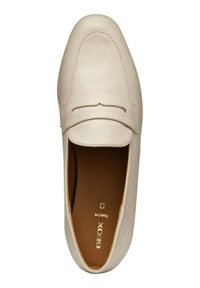 Mocasines de cuero color beige claro con punta redonda y detalle de tira decorativa. Textura suave y costuras mínimas. Nombre de la marca "GEOX" grabado en el interior.