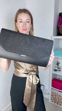 Geantă de mână din piele neagră cu un finisaj texturat, având un design cu clapetă netedă și un accent subtil de aur.