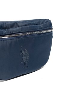 Námořnická modrá nylonová taška se zipovým víkem. Obsahuje vyražené logo a hladký povrch. Jednoduchý obdélníkový tvar, navržený pro kompaktní skladování.