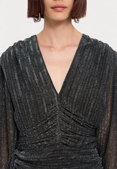 Black dress with a deep V-neckline, textured fabric, and ruched detailing at the waist. Sheer long sleeves with metallic thread accents.