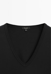 Sort V-hals skjorte med en smal ribbet krave, der viser et lille label med teksten "Massimo Dutti Made in Portugal" ved halsudskæringen.