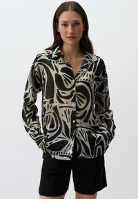 Camicia button-up nera e crema con motivi astratti, maniche lunghe, colletto e vestibilità rilassata, realizzata in un tessuto leggero.