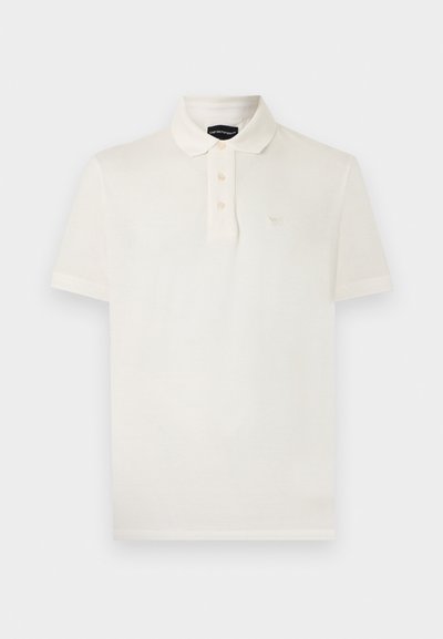 Balta īsroku polokrekls ar trim pogām un nelielu izšūtu logotipu uz kreisās krūšu puses.