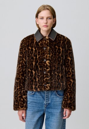 Chaqueta de pelo sintético con estampado de leopardo y un cuello oscuro, con botones en la parte delantera y un diseño corto, combinada con unos pantalones vaqueros de mezclilla azul. Apariencia texturizada y cálida.