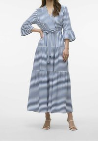 Vestido largo a rayas azul y blanco con escote en V, cinturón atado en la cintura y mangas acampanadas. Diseño en capas con una silueta fluida.