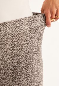 Leggings extensibles à motifs dans des tons de beige et de marron, avec un design texturé ressemblant à de la peau de serpent et une taille élastique.