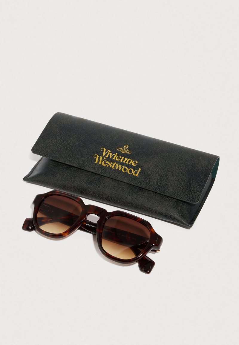 Occhiali da sole tartarugati con lenti a gradiente marrone, dotati di una montatura rettangolare spessa. Accompagnati da un astuccio in pelle verde con logo dorato.