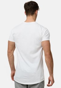Hvid bomulds-t-shirt, korte ærmer, rund hals, lige kant. Glat tekstur med en klassisk pasform, vist fra ryggen. Ingen synlige logoer.