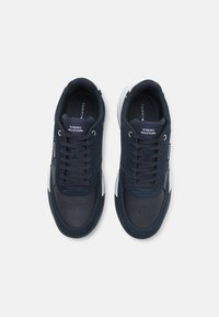 Sneaker navy in camoscio e pelle, con un design semplificato, area delle dita perforata e accenti bianchi sulla suola e sui lati.
