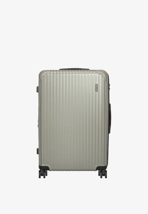 Duża srebrna walizka z twardą obudową z pionowymi żłobieniami, czterema czarnymi kółkami i czarnymi uchwytami na białym tle.