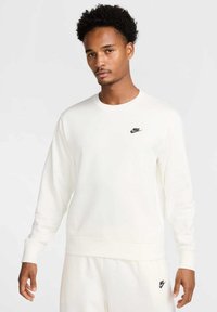 Felpa bianca a girocollo realizzata in tessuto morbido, con un piccolo logo Nike nero sul petto e polsini e orlo a costine.