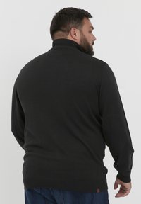 Mustmustel musthave kõrge kaelusega, soonikkoes mansettide ja servaga. Sellel on sile tekstuur ja nüansirikas aktsent allosas.