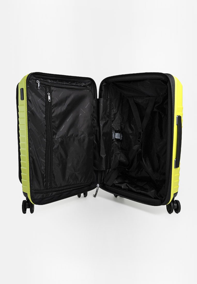 Maleta rígida de color amarillo brillante con acentos en negro, que cuenta con un compartimento con cremallera, correas elásticas y ruedas de giro suave.