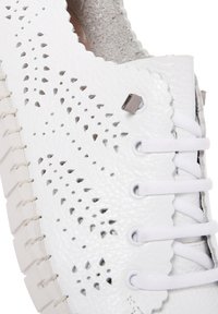 Chaussure en cuir blanc avec des motifs perforés et des bords festonnés. Comprend des lacets blancs et une semelle en caoutchouc avec des coutures visibles.