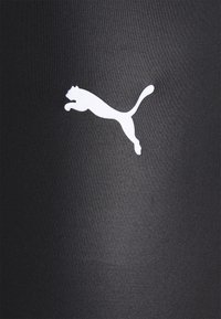 Leggings deportivos negros con una textura suave, diseño ajustado y un prominente logo blanco de Puma en el costado.