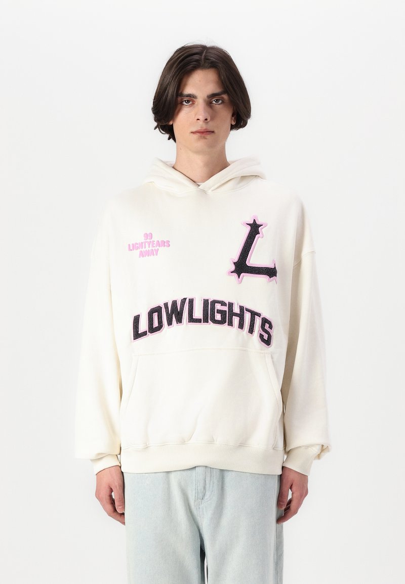 Felpa con cappuccio crema con testo ricamato in rosa e nero: "99 LIGHTYEARS AWAY" e "LOWLIGHTS". Presenta una tasca a marsupio sul davanti.