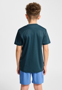 Mörkblå kortärmad träningsskjorta med rund halsringning, parat med ljusblå shorts. Slät textur med subtila sömdetaljer på axlarna.