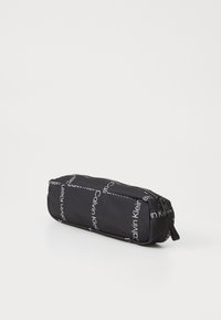 Astuccio nero realizzato in tessuto durevole, con un motivo ripetuto di logo "Calvin Klein" bianco e chiusura con zip. Forma rettangolare.