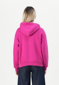 Hooded dukserica u vibrantnoj ružičastoj boji, s opuštenim krojem i rebrastim manžetama. Izrađena od mekanog materijala s klasičnim dizajnom.