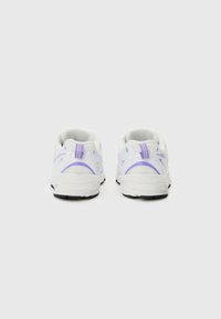 Baskets de sport blanches avec une tige en maille, dotées de accents violets et de motifs texturés sur les côtés et le talon, semelles noires et forme arrondie.