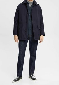 Navyblauwe jas met een recht model, knoopsluiting en twee zijzakken. Draag het over een donker shirt en combineer het met donkere jeans en sneakers.