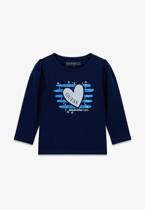 Chemise bleu marine à manches longues en coton biologique avec des épaules bouffantes, ornée d'un cœur et de l'inscription "GUESS" en bleu clair et argent, agrémentée d'étoiles.