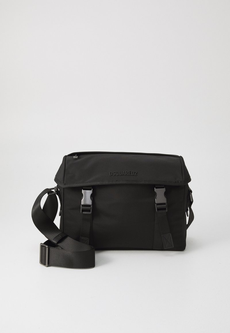 Geantă de umăr din nylon negru cu închidere cu clapetă, curea ajustabilă și accesorii metalice. Prezintă un logo gravat pe partea din față.